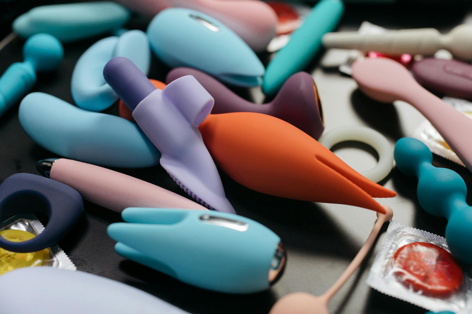 Eine Person hält einen rosafarbenen Vibrator, umgeben von Kunstbüchern, was intime und persönliche Momente darstellt.